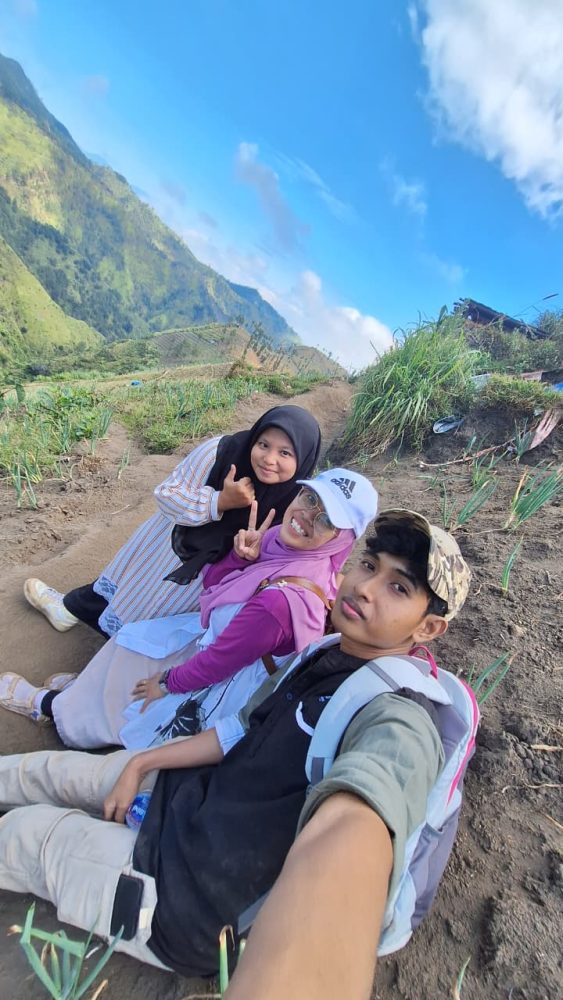 Momen Refleksi: Tentang Perjalanan, Bukan Sekadar Tujuan Di sabana, aku jadi mikir. Hidup kadang mirip perjalanan ke Bukit Premium ini. Kita bisa memilih jalan cepat, praktis, tapi mungkin ada cerita yang terlewat. Atau kita pilih jalan yang lebih susah, lebih lama, tapi di sepanjang jalan kita belajar banyak hal. Aku belajar sabar, belajar menikmati setiap langkah, bahkan belajar tertawa di tengah lelah. Dan yang terpenting, aku merasa lebih “nyambung” dengan alam. Bukit, angin, dan sabana seakan mengajarkan untuk pelan-pelan, menikmati, dan mensyukuri setiap hal kecil. Pulang: Jalan Ditutup, Cerita Bertambah Setelah puas menikmati sabana, aku akhirnya harus turun. Total perjalanan sekitar 12.000 langkah. Alhamdulillah melebihi target harian. Perjalanan pulang tentu lebih mudah karena jalannya menurun, tapi tetap saja lutut dan kaki lumayan protes. Namun kali ini aku sudah nggak peduli. Hati terlalu bahagia, dan pikiranku masih penuh dengan pemandangan cantik tadi. Sesampainya di bawah, aku menengok sebentar ke arah atas. Aku senyum sendiri. “Aku berhasil jalan kaki sampai atas,” batinku bangga. Bukan sekadar sampai, tapi juga membawa pulang banyak cerita Entah mengapa, perjalanan pulang rasanya lebih cepat dan lebih ringan. Alhamdulillah kami berhasil PP jalan kaki alias tanpa naik ojek. Sampai ke parkiran, kami pulang melewati Nongkojajar lagi. Namun, ternyata kami harus berhadapan dengan kejutan: banyak jalan ditutup. Rupanya ada acara lokal, mungkin berkaitan dengan truk-truk sound horeg yang kulihat tadi pagi. Resiko kalau travelling di Bulan Agustus. Wkkwkw.. Kami terpaksa muter lewat jalur lain, lebih panjang, lebih berliku. Awalnya kesal, tapi lama-lama aku tertawa sendiri. “Ya sudah, toh semakin lama di jalan, semakin panjang ceritanya,” batinku. Kadang perjalanan memang suka bercanda dengan kita, memberi kejutan di luar rencana. Jadiii.. yang awalnya kami mau lewat Nongkojajar, jadinya lewat Pakis dan Sawojajar. Langsung masuk tol menuju Surabaya. Bener-bener di luar skenario. Alhamdulillah perjalanan melewati Pakis aman tidak ada jalan ditutup. Keunikan alam Bukit Premium: Hamparan sabana luas yang hijau segar, mirip seperti Bukit Wairinding di Sumba Lanskapnya menghadirkan perbukitan berundak yang dramatis, dengan kabut tipis di pagi hari dan pemandangan Gunung Bromo, Semeru, hingga Arjuno dari kejauhan Cocok banget untuk foto-foto estetik, berburu sunrise atau sunset, piknik ringan, atau bahkan camping ground sederhana Tiket masuk dan parkir murah meriah buat scenery “premium”. Trekking ramah untuk pemula dan anak-anak, cukup landai dan pemandangannya “film alam” beneran Banyak spot instagramable Tips Kecil dari Perjalanan Premium Buat teman-teman yang ingin merasakan perjalanan ke Bukit Premium ala jalan kaki, ada beberapa hal kecil yang bisa jadi bekal: Bawa air minum cukup Percayalah, air mineral bisa jadi lebih nikmat daripada minuman manis apapun setelah tanjakan panjang. Pakai masker Selama perjalanan ada bagian yang penuh debu. Kenakan sepatu atau sandal gunung Jalan tanah dan bebatuan licin kalau habis hujan. Siapkan jaket tipis Udara di atas dingin, terutama pagi atau sore. Bawa snack ringan. Energi ekstra akan sangat berguna. Datang pagi atau sore. Sunrise dan sunset di sini katanya luar biasa. Tanya warga soal kondisi jalan. Siapa tahu ada penutupan jalur, jadi bisa siap dengan alternatif. Perjalanan kali ini mengajarkanku banyak hal. Bahwa premium itu bukan soal uang, tapi soal pengalaman. Premium adalah ketika kita tertawa di tengah capek, ketika kita menemukan keindahan di balik peluh, ketika kita menerima kejutan jalan yang ditutup tanpa mengeluh. Bukit Keciri, sang Sabana Guntur Loreng, mungkin hanya sebuah bukit di Pasuruan. Tapi bagiku, ia adalah guru kecil yang mengingatkan: nikmatilah proses, jangan buru-buru. Karena kadang, justru langkah-langkah paling beratlah yang membuat kita merasa paling hidup. Dan saat aku menoleh sekali lagi ke atas bukit sebelum pulang, aku tersenyum. Perjalanan ini bukan hanya tentang sampai, tapi tentang bagaimana aku melewati semua, dengan kaki yang pegal, hati yang penuh, dan cerita yang kini abadi dalam ingatan.